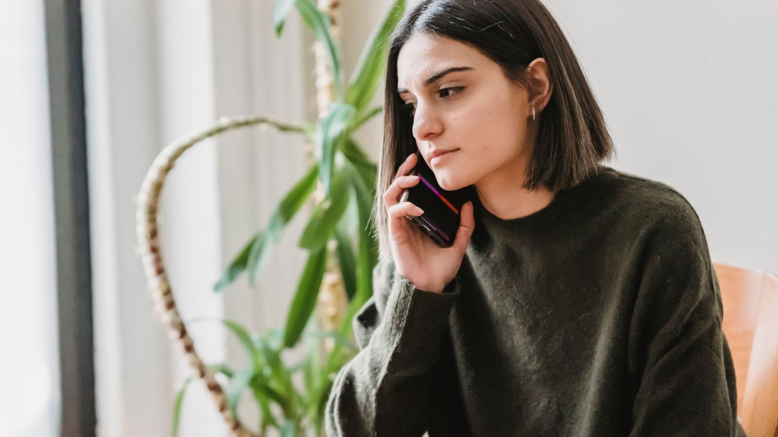 Clinical trial participant speaking by phone during a follow-up conversation at home.